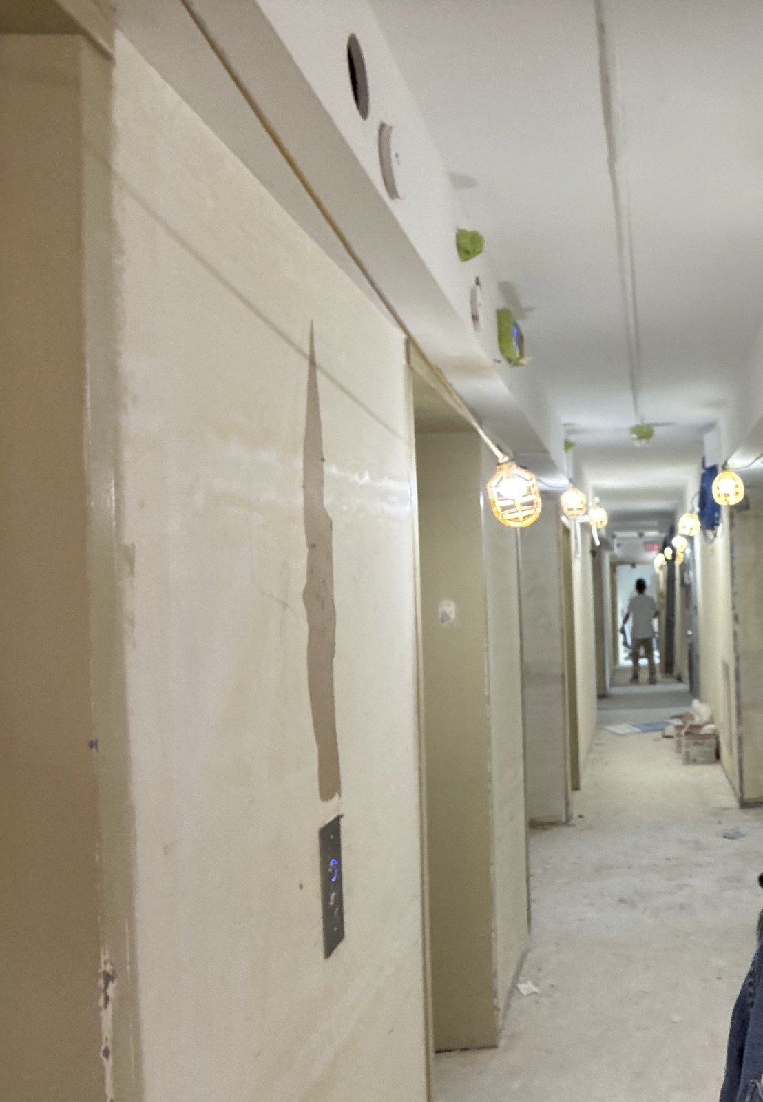 Multi-unit residential corridor mid-construction with temporary lighting