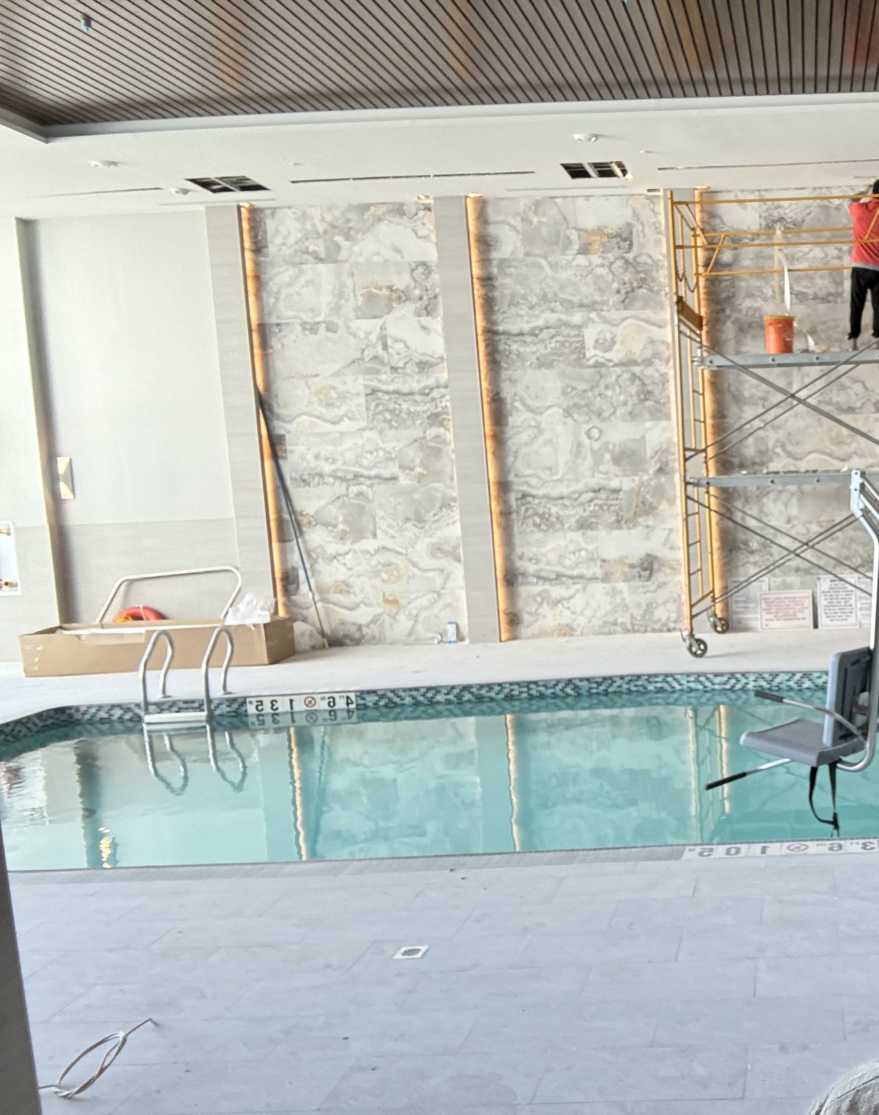 Indoor pool and spa with active wall-tile installation in the background